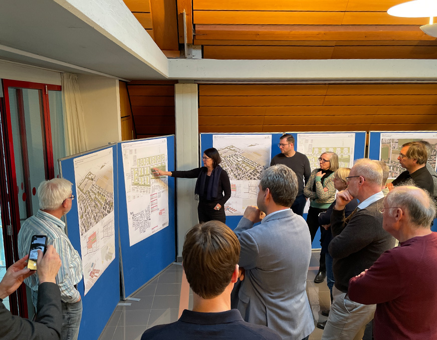 Teilnehmende betrachten und diskutieren städtebauliche Entwürfe auf Stellwänden bei einem Workshop