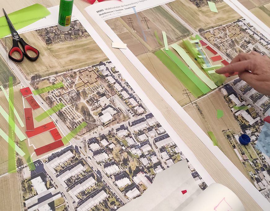 Planung eines Wohngebiets mit farbigen Papiermarkierungen und Entwurfselementen auf einem Tisch
