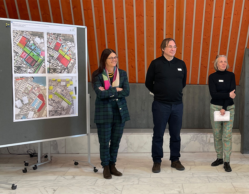 Mitglieder des Beirats bei einer Präsentation zu städtebaulichen Planungen vor einer Kartenübersicht