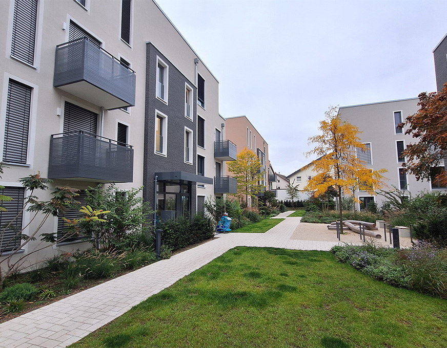 Modernes Wohnquartier mit Mehrfamilienhäusern, Wegen und begrünten Außenanlagen zwischen den Gebäuden