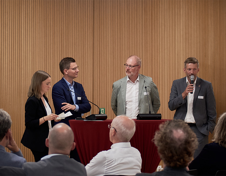 Personen sprechen bei einer Veranstaltung vor Publikum über das Modellvorhaben MORO Fläche