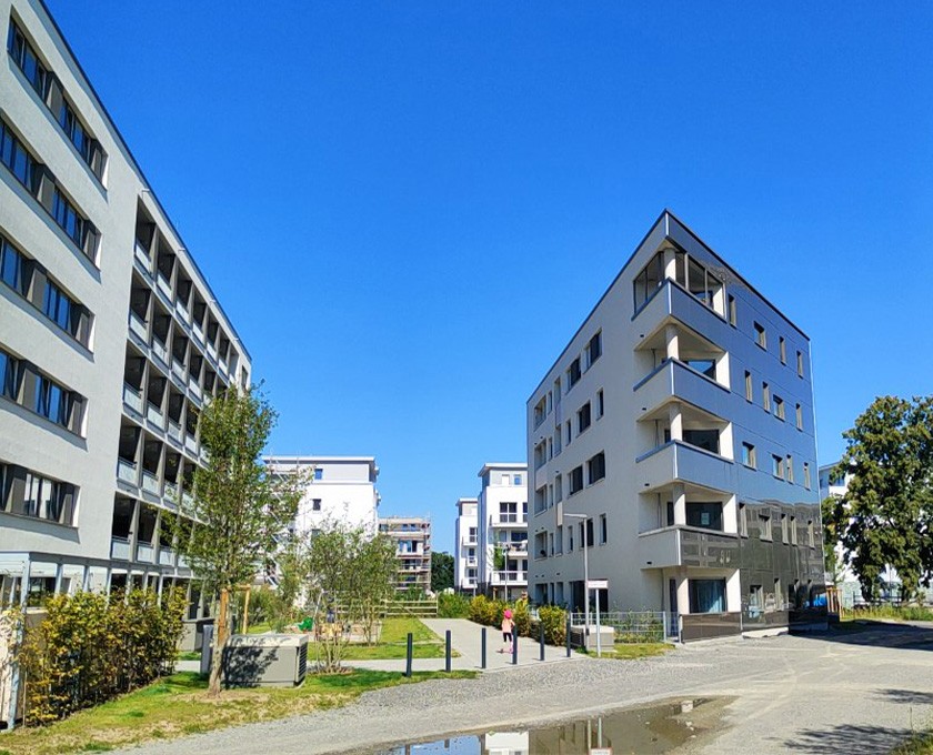 Modernes Wohnquartier mit mehreren mehrstöckigen Gebäuden, Grünflächen und Fußwegen unter klarem blauem Himmel