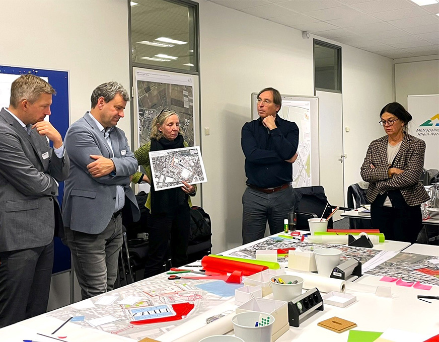 Fachleute besprechen städtebauliche Planungen anhand von Karten und Entwürfen in einem Workshopraum