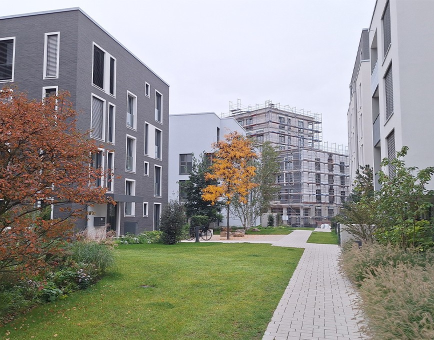 Neues Wohnquartier mit Mehrfamilienhäusern, Grünflächen und einem Gebäude im Bau mit Gerüst